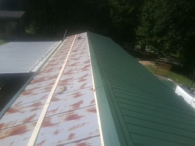 Old rusted panels beside newly installed green metal roofing — Wind Damage Roof Repair by Roofing Brothers in Gunnison