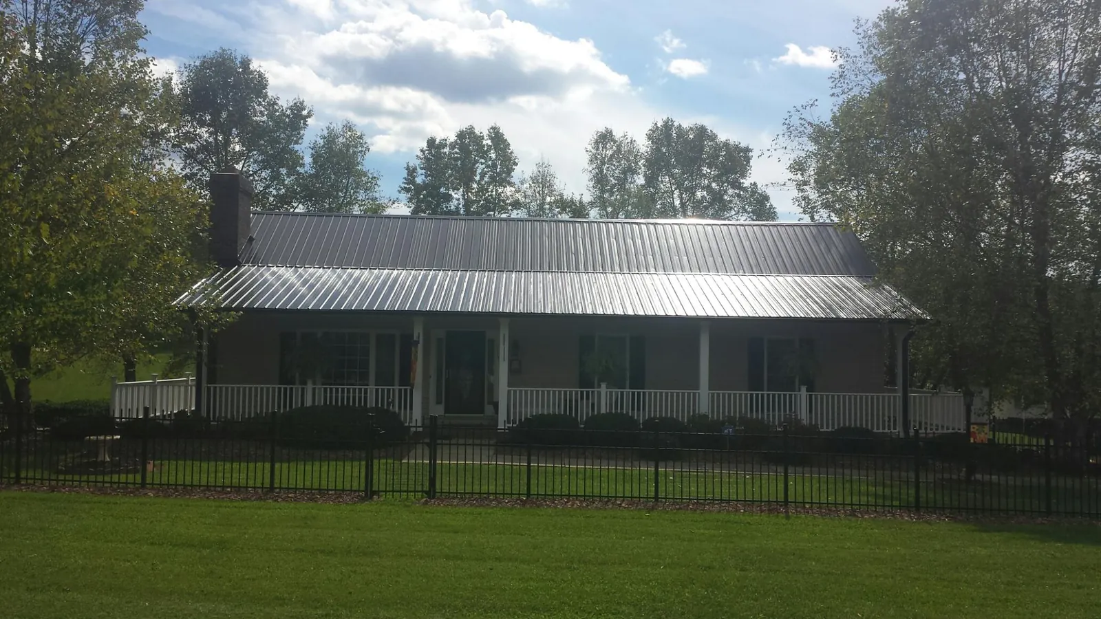 Gray metal roof on a brick ranch with a full width front porch — Gutter Guard Installation work by our crew in Gunnison