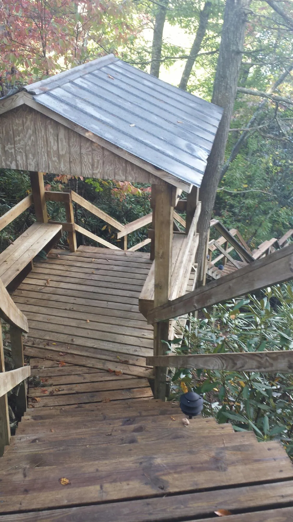 Metal roofed shelter over wooden steps on a wooded walkway — Skylight Repair & Installation work by our crew in Gunnison