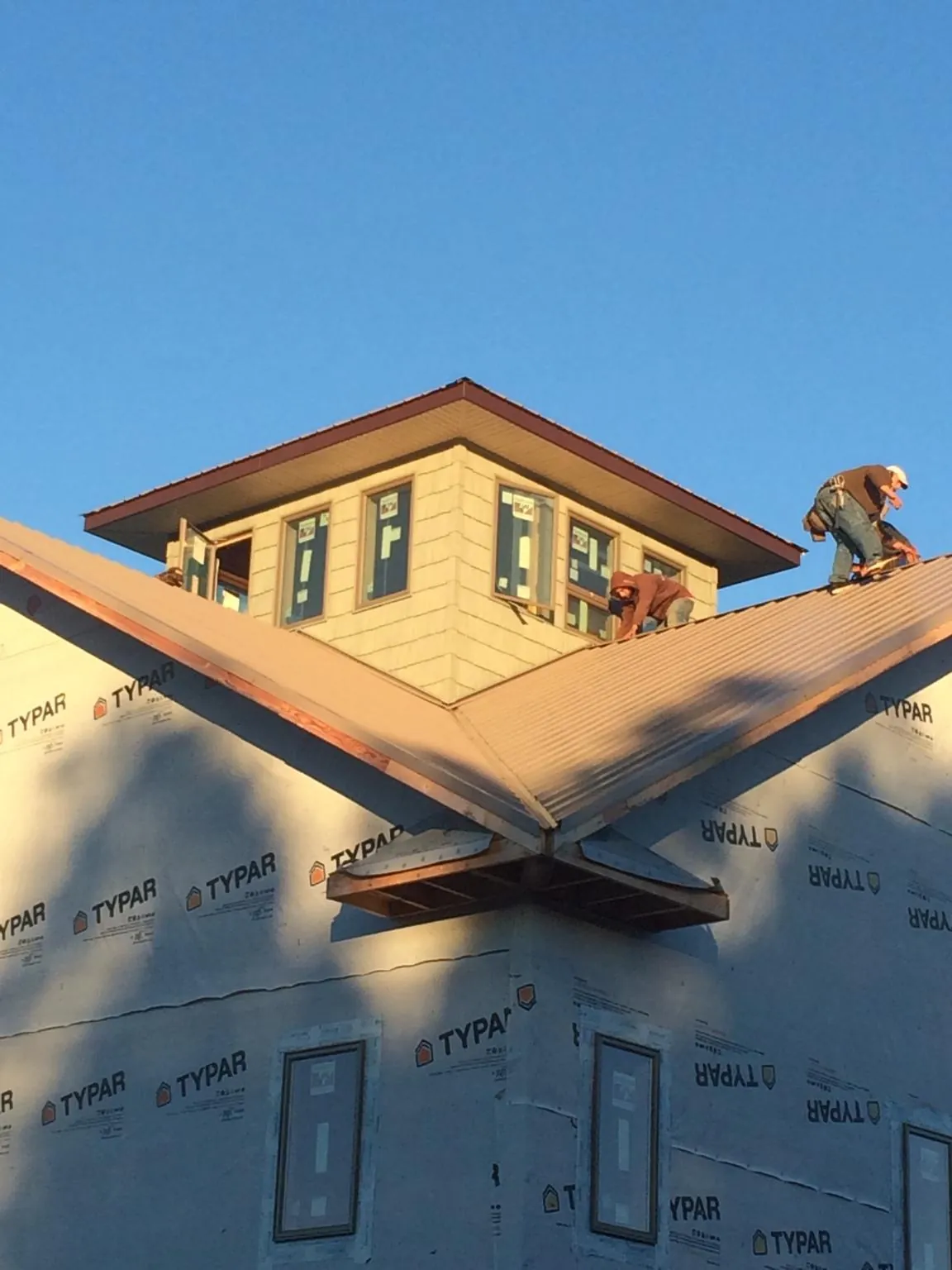 Roofers working around a rooftop cupola on a new metal roof at sunset — Roof Waterproofing in Gunnison by Roofing Brothers